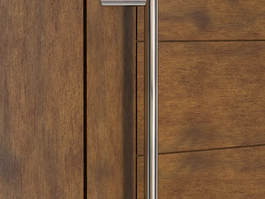 Vertical satin stainless bar pull mounted on a dark walnut panelled door, lit softly from the left.