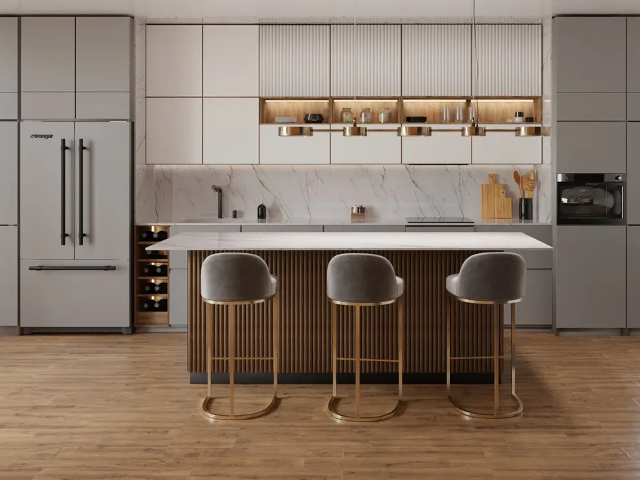Wide view of a light kitchen with pale upper cabinets, a marble backsplash, lit open shelving, a fluted wood island and three grey bar stools on brass frames over a warm oak floor.