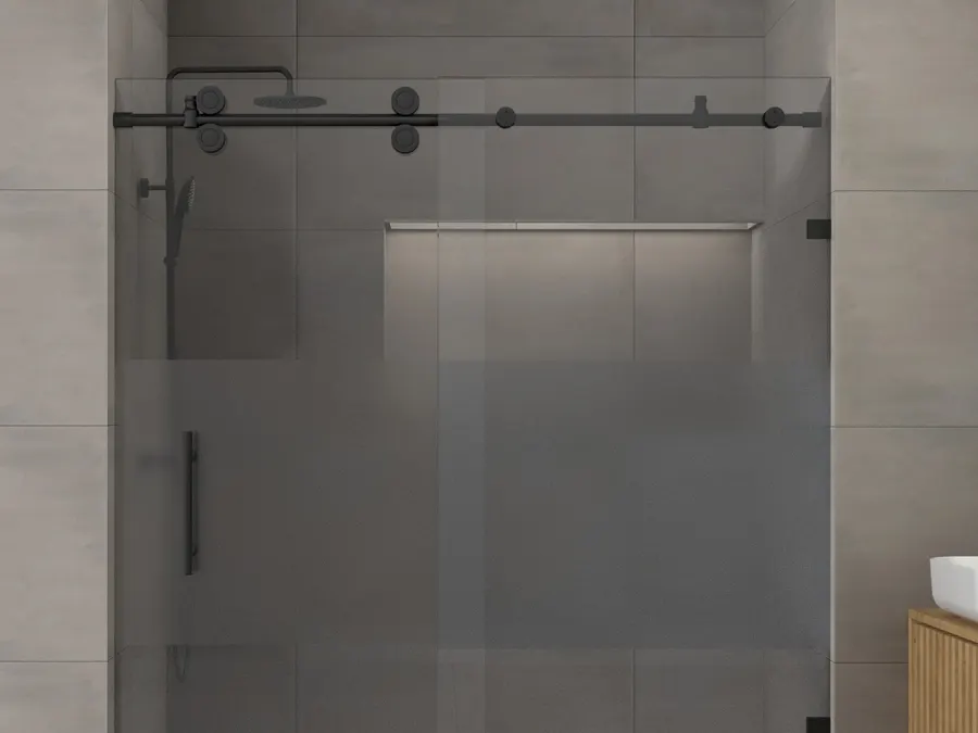 A frameless glass sliding shower door hung on a matte black roller track and rail in a light tiled bathroom, with a black rain head and hand shower behind the glass.